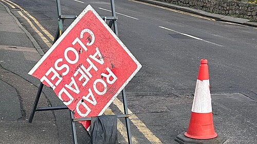 Broken Road Ahead Closed sign with traffic cone